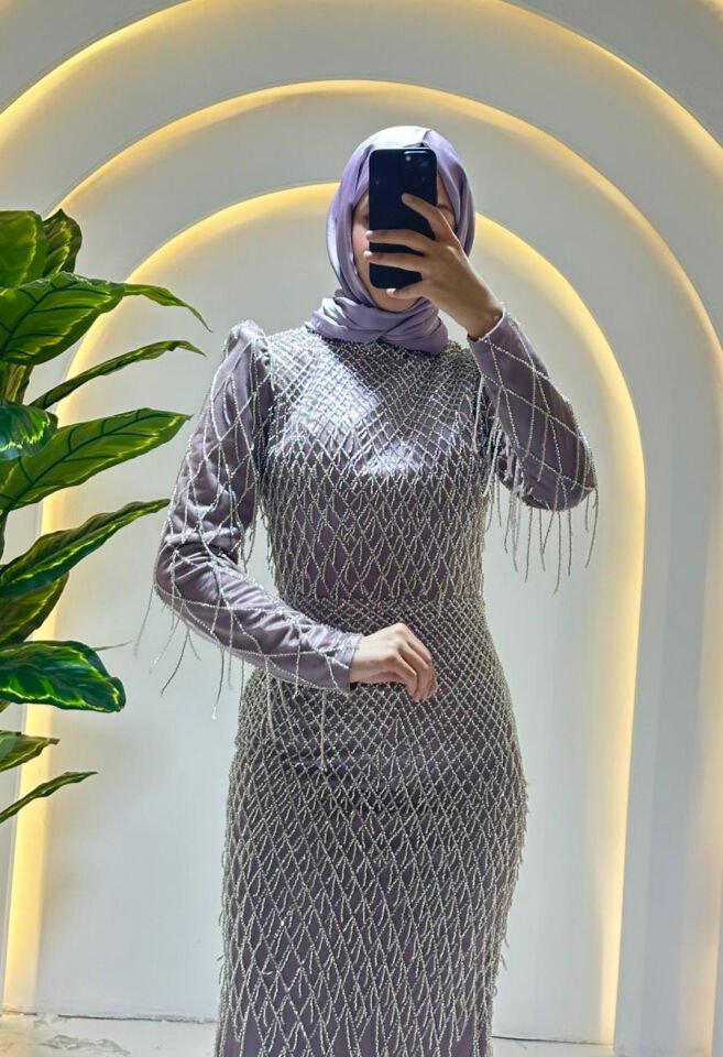 Baştan aşağıya püskül ve boncuk işlemelerle (saçaklı görünümde) süslenmiştir Omuz kısımları hafif kabartmalı/vatkalı yakası yüksek kesimdir Lila Abiye 44