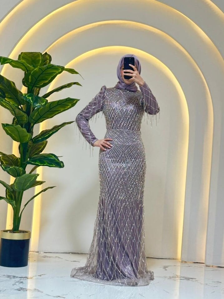 Baştan aşağıya püskül ve boncuk işlemelerle (saçaklı görünümde) süslenmiştir Omuz kısımları hafif kabartmalı/vatkalı yakası yüksek kesimdir Lila Abiye 44