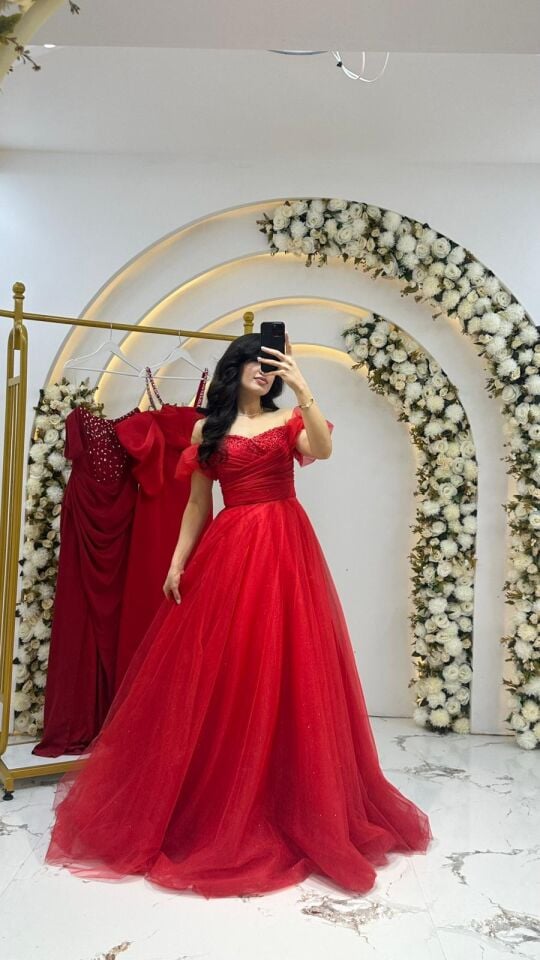 Kırmızı tül kumaştan yapılmış, kabarık etekli ve omuzları açık bir Kırmızı Abiye 42