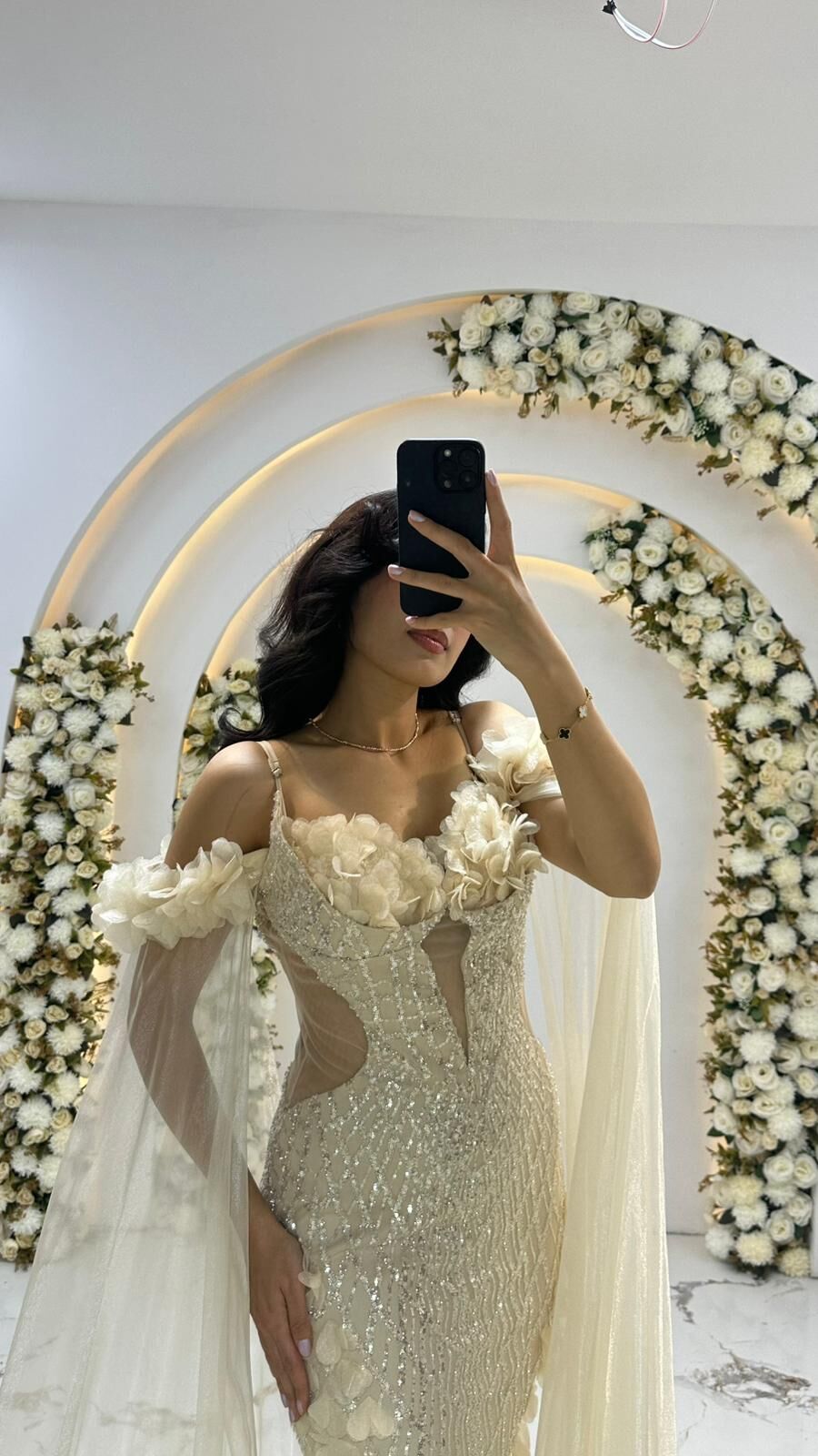 Omuzlardan başlayıp yere kadar inen, tül veya organze kumaştan uzun pelerin/kanatlara sahiptir. Korsaj ve etek kısmında, üç boyutlu çiçek aplikeleri ve incilerle yoğun Krem Abiye 42