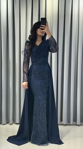 Uzun kollu, pullu ve payetli balık kesim Lacivert Abiye elbise. Belden düşümlü, sade kumaştan uzun pelerin kuyruk detayı mevcuttur. 44