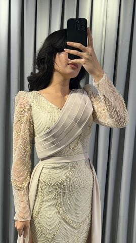 Uzun kollu, pullu ve payetli balık kesim Krem Abiye elbise. Belden düşümlü, sade kumaştan uzun pelerin kuyruk detayı mevcuttur. 44