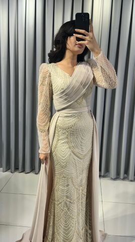 Uzun kollu, pullu ve payetli balık kesim Krem Abiye elbise. Belden düşümlü, sade kumaştan uzun pelerin kuyruk detayı mevcuttur. 44