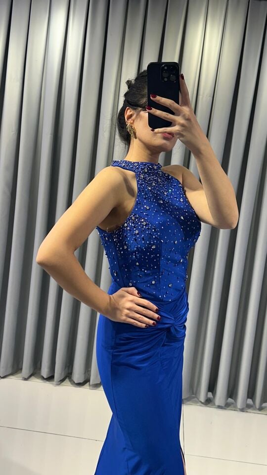 Halter yaka (yüksek, boyundan bağlamalı)Yoğun boncuk ve taş işlemeli (parlak/ışıltılı) Vücuda oturan, yüksek yırtmaçlı uzun etek Yırtmacın hemen üstünde büzgülü/düğüm görünümlü  Mavi Abiye 42