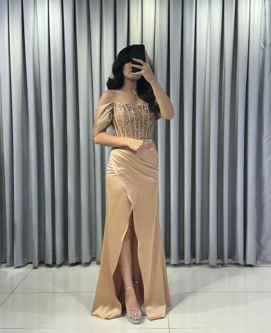 Omuzları açık vücuda oturan balık Göğüs kısmı ve korsaj, parlak boncuk pul işlemelerle yoğun bir şekilde süslü Ön kısımda yüksek yırtmaç Saten Gold Abiye 42