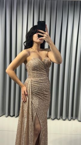 Baştan sona ışıltılı ve pullu Göğüs kısmında büzgülü ve vücudu saran kesim; yan kısımda, yırtmacın hemen yanında toplanmış, asimetrik bir etek detaylı Bej Abiye 40