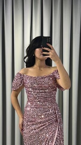 Baştan sona pullu ve payetli, parlak bir görünüme sahip Omuzları açık (kayık yaka veya düşük omuz) bir kesime sahip Bel ve kalça hizasında drapeli yüksek yırtmaç detaylı Pembe Abiye 42