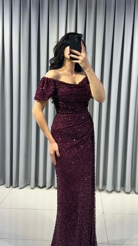 Baştan sona pullu ve payetli, parlak bir görünüme sahip Omuzları açık (kayık yaka veya düşük omuz) bir kesime sahip Bel ve kalça hizasında drapeli yüksek yırtmaç detaylı Bordo Abiye 42