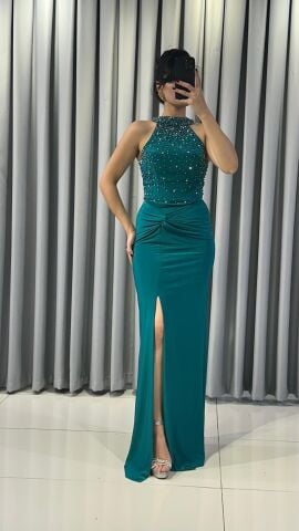 Halter yaka (yüksek, boyundan bağlamalı)Yoğun boncuk ve taş işlemeli (parlak/ışıltılı) Vücuda oturan, yüksek yırtmaçlı uzun etek Yırtmacın hemen üstünde büzgülü/düğüm görünümlü Yeşil Abiye 42