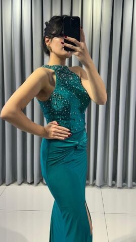 Halter yaka (yüksek, boyundan bağlamalı)Yoğun boncuk ve taş işlemeli (parlak/ışıltılı) Vücuda oturan, yüksek yırtmaçlı uzun etek Yırtmacın hemen üstünde büzgülü/düğüm görünümlü Yeşil Abiye 42