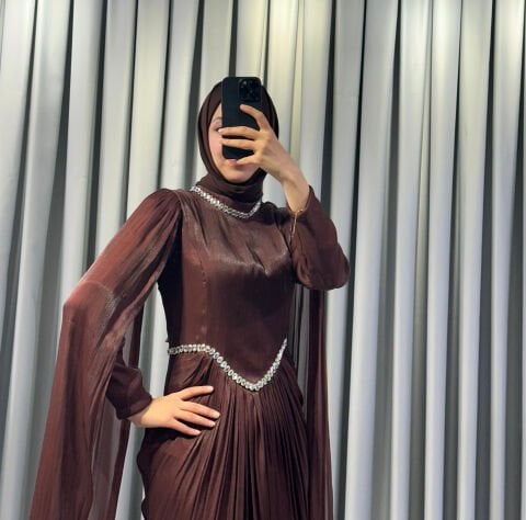 Uzun pelerin kollu, taş detaylı kemerli ve pileli Kahverengi Tesettür Abiye elbisedir. 44