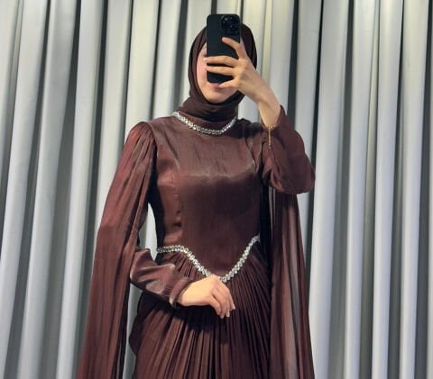 Uzun pelerin kollu, taş detaylı kemerli ve pileli Kahverengi Tesettür Abiye elbisedir. 44