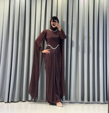 Uzun pelerin kollu, taş detaylı kemerli ve pileli Kahverengi Tesettür Abiye elbisedir. 44