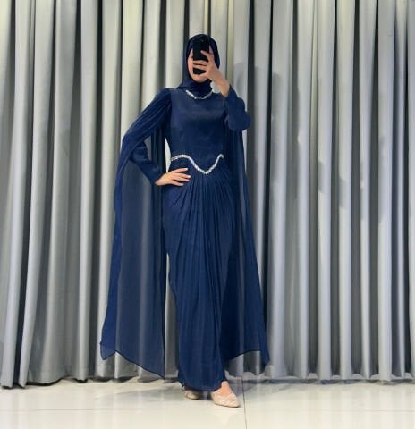 Uzun pelerin kollu, taş detaylı kemerli ve pileli Mavi Tesettür Abiye elbisedir. 44
