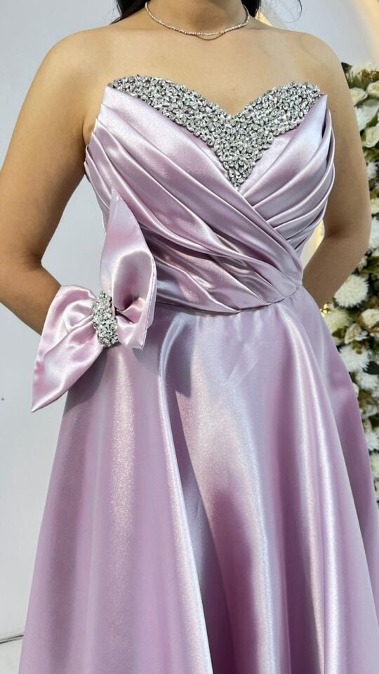 Kalp yaka kesimi üzerinde gümüş rengi taş ve boncuk işlemeleri Bel kısmında büyük, gösterişli bir fiyonk ve taşlı toka detayı mevcuttur A kesim prenses model Pudra Pembe Abiye 44