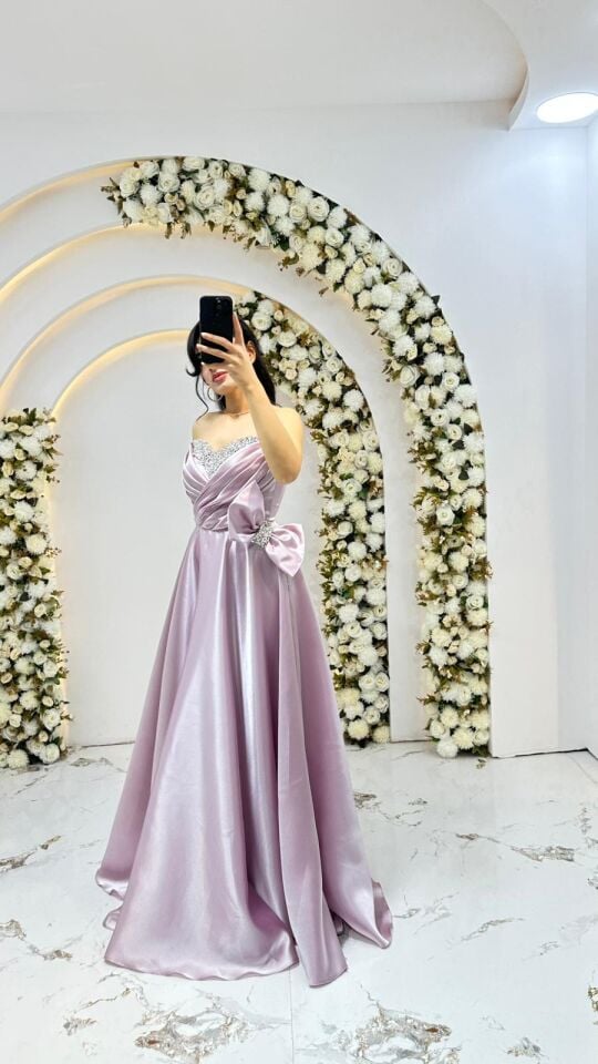Kalp yaka kesimi üzerinde gümüş rengi taş ve boncuk işlemeleri Bel kısmında büyük, gösterişli bir fiyonk ve taşlı toka detayı mevcuttur A kesim prenses model Pudra Pembe Abiye 44