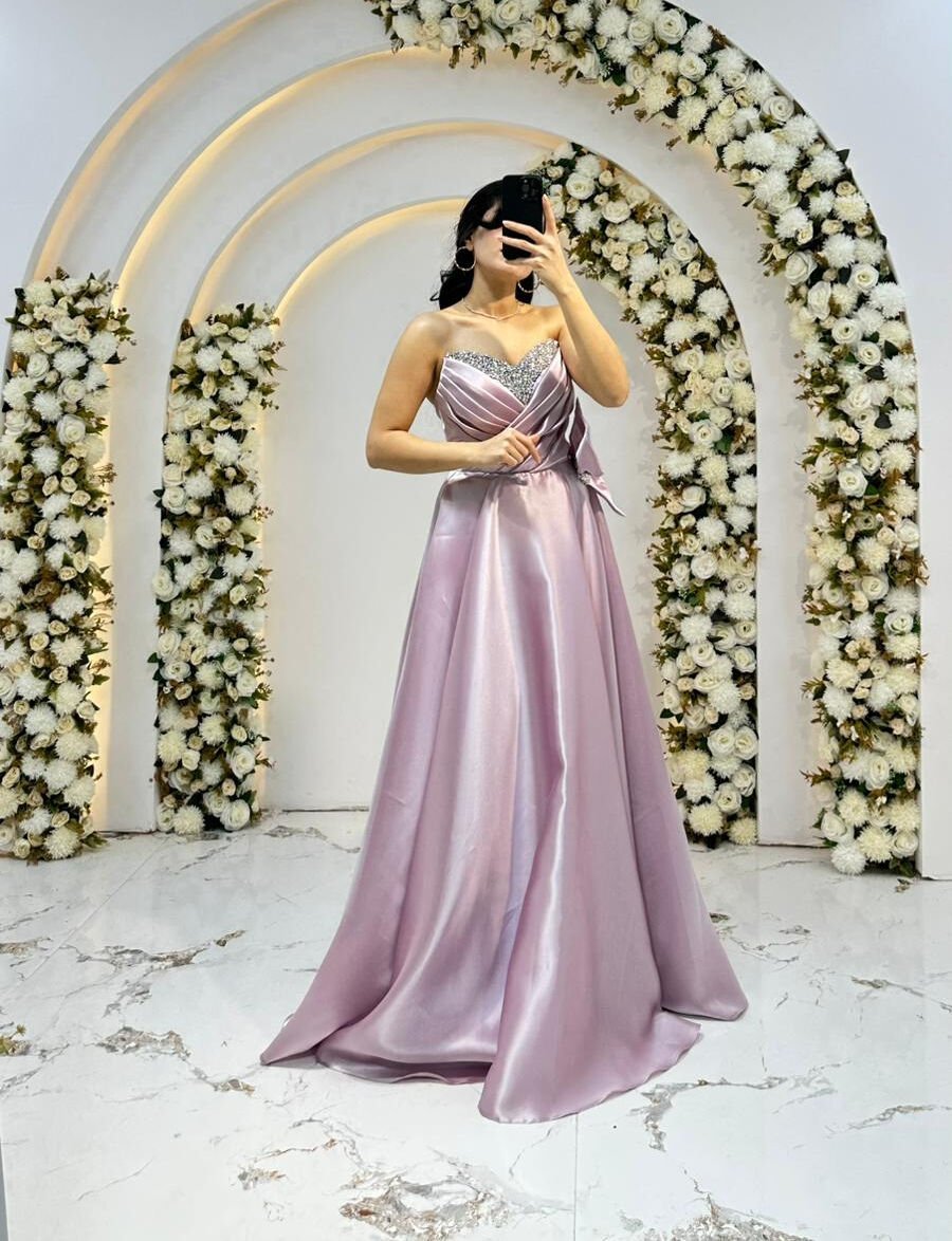 Kalp yaka kesimi üzerinde gümüş rengi taş ve boncuk işlemeleri Bel kısmında büyük, gösterişli bir fiyonk ve taşlı toka detayı mevcuttur A kesim prenses model Pudra Pembe Abiye 44