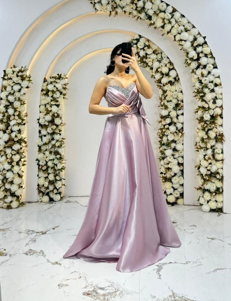 Kalp yaka kesimi üzerinde gümüş rengi taş ve boncuk işlemeleri Bel kısmında büyük, gösterişli bir fiyonk ve taşlı toka detayı mevcuttur A kesim prenses model Pudra Pembe Abiye 44