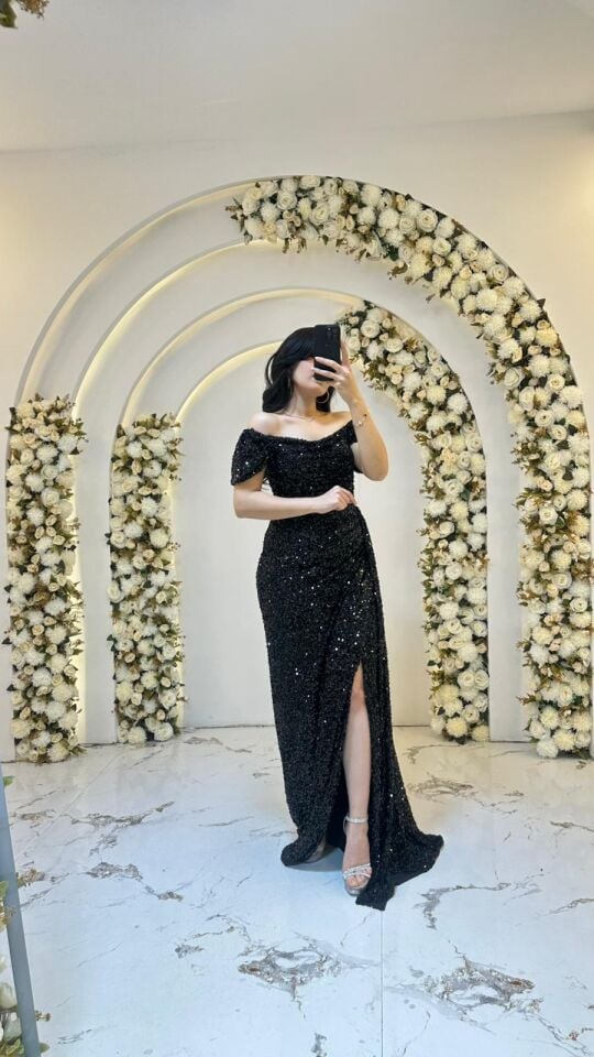 Omuzları açık bırakan zarif madonna yaka kesimine sahiptir Bel bölgesindeki drapeli  hafif yırtmacı  Siyah pul payet Abiye 44