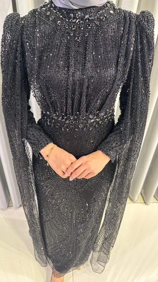 Kristal taş işlemeli Vücuda oturan, balık kesim Parlak, Siyah tonlarında yoğun pul ve payet işlemeleri bulunur Omuzları hafif kabarık Siyah  Abiye 48