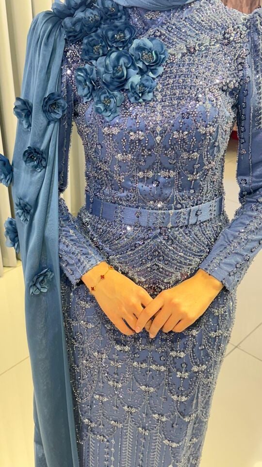 Baştan ayağa boncuk ve pul işlemeleri ile yoğun süslemeli Yüksek yaka Omuzdan başlayıp bele ve yere kadar uzanan, 3D çiçek aplikeleriyle süslü uzun bir şal/pelerin detayı bulunan Vücuda oturan, balık model Mind Yeşili Abiye 44